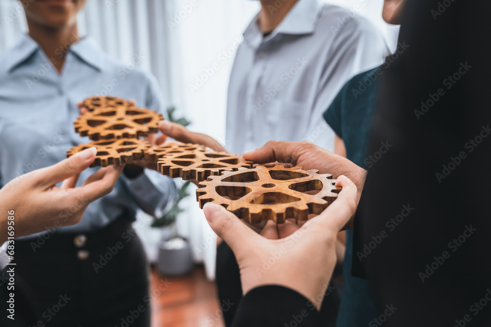 Office worker holding cog wheel as unity and teamwork in corporate workplace concept. Diverse colleague business people showing symbol of visionary system and mechanism for business success. Concord