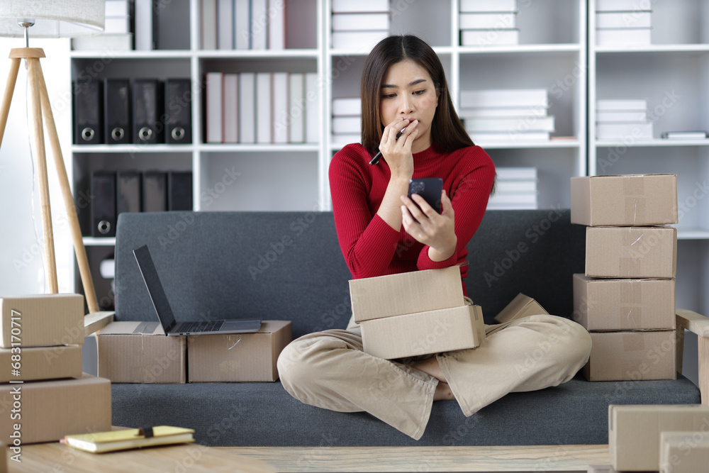 Asian woman selling online from home checking internet order on smartphone at home. Asian woman selling online from home checking internet order on smartphone at home.