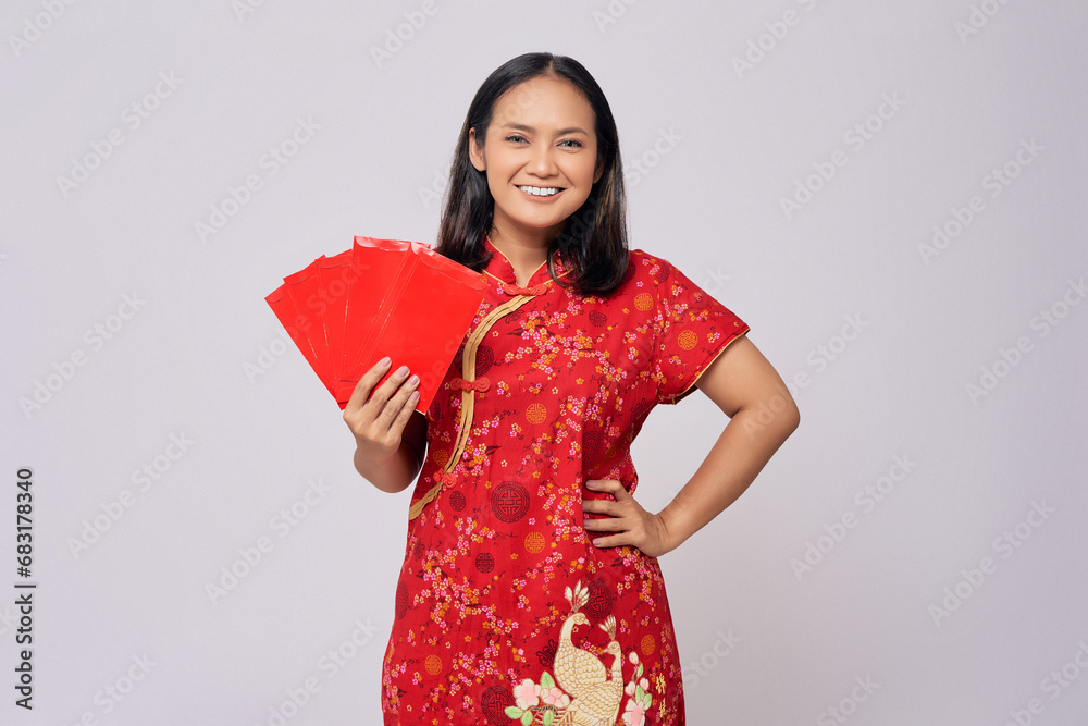 Smiling young Asian woman wearing a traditional cheongsam qipao dress holding angpao or red packet monetary gift isolated on white background. Happy Chinese New Year Smiling young Asian woman wearing a traditional cheongsam qipao dress holding angpao or red packet monetary gift isolated on white background. Happy Chinese New Year