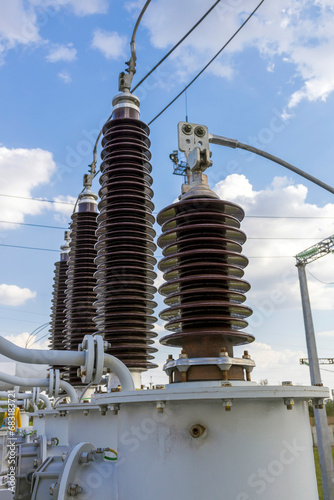 High and low voltage transformer bushings with electrical insulation and electrical equipment at a power substation.