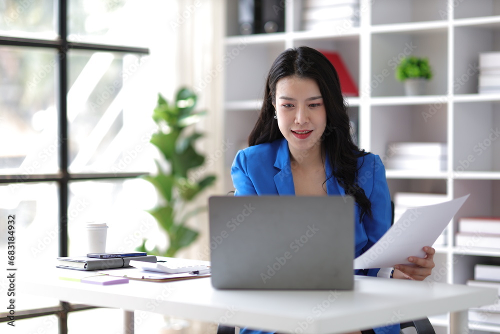 Attractive asian businesswoman secretary working with laptop and paperwork in office. Attractive asian businesswoman secretary working with laptop and paperwork in office.