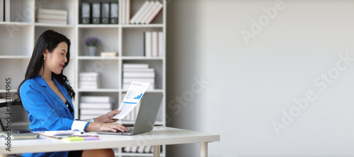 Attractive asian businesswoman secretary working with laptop and paperwork in office.