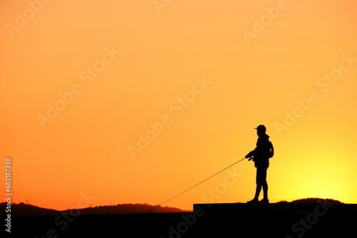 夕陽に染まる釣り人のシルエット