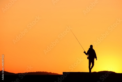 夕陽に染まる釣り人のシルエット