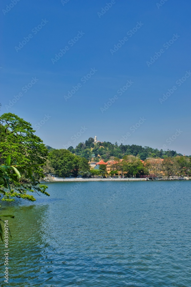 KANDY, SRI LANKA - FEBRUARY 10, 2021: View on Kandy lake and big Buddha on top of the hill. Kandy is home of The Temple of the Tooth Relic, one of the most sacred Buddhist places of worship. 
