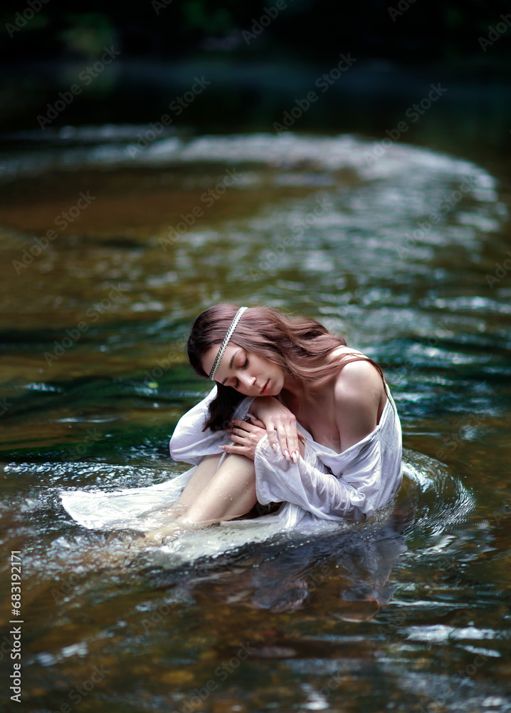 Fototapeta premium Young long haired woman in slavic style white nightgown with open shoulders and hair band sitting in river in dark forest. Tradinional Ivan Kupala outfit. Fairytale portrait of a girl