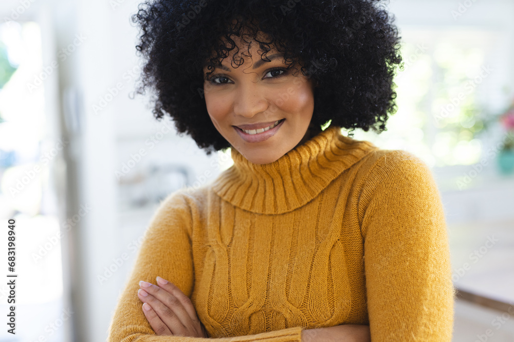 Fototapeta premium Happy african american woman standing with arms crossed at home, copy space