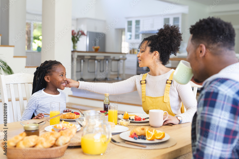 Happy african american family having fresh fruits snack in dining room at home, copy space