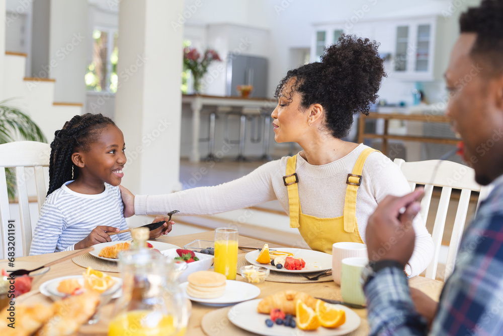 Happy african american family having fresh fruits snack in dining room at home, copy space