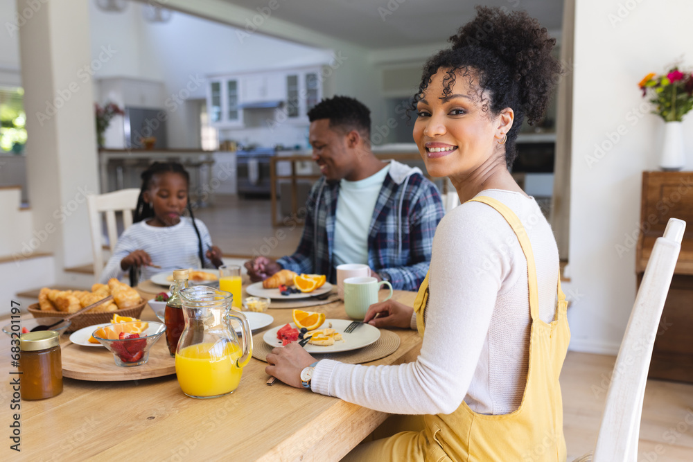 Happy african american woman sitting at table, having a snack with family at home, copy space Happy african american woman sitting at table, having a snack with family at home, copy space