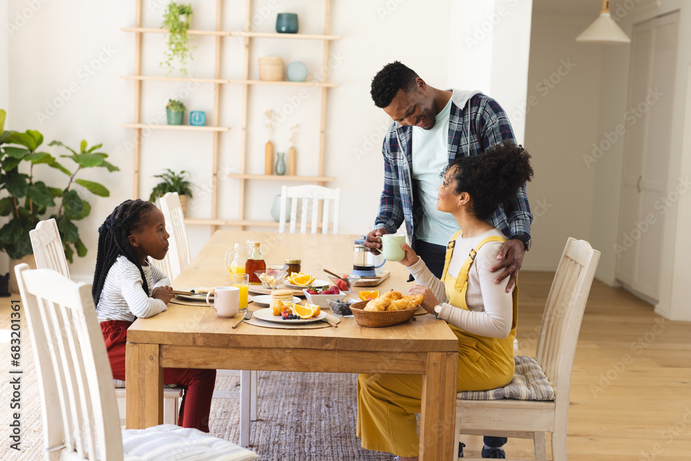 African american man pouring tea to cup at table during breakfast in morning at home, copy space African american man pouring tea to cup at table during breakfast in morning at home, copy space