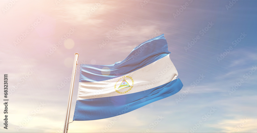 Nicaragua national flag waving in beautiful sky. The symbol of the state on wavy silk fabric.