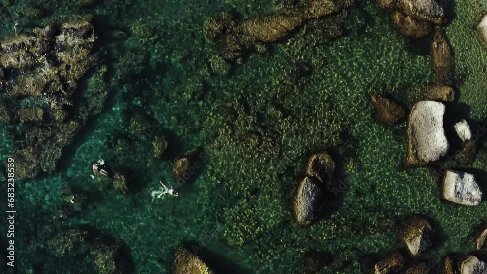 Aerial drone shot of the ocean coastline scattered with rocks and swimmer with snorkle Aerial drone shot of the ocean coastline scattered with rocks and swimmer with snorkle