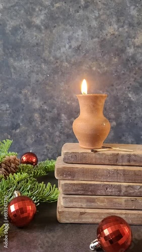 Rustic Christmas greeting Card with Christmas candle in clay pot on black background. Vertical video with XMAS decoration in rerto style. XMAS mood.  photo