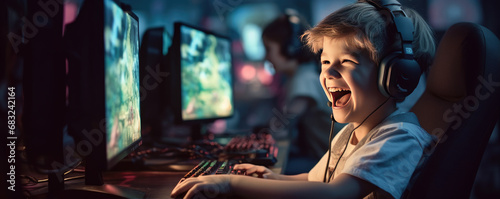 Happy boy is excited playing games on computer. Playing PC games concept photo