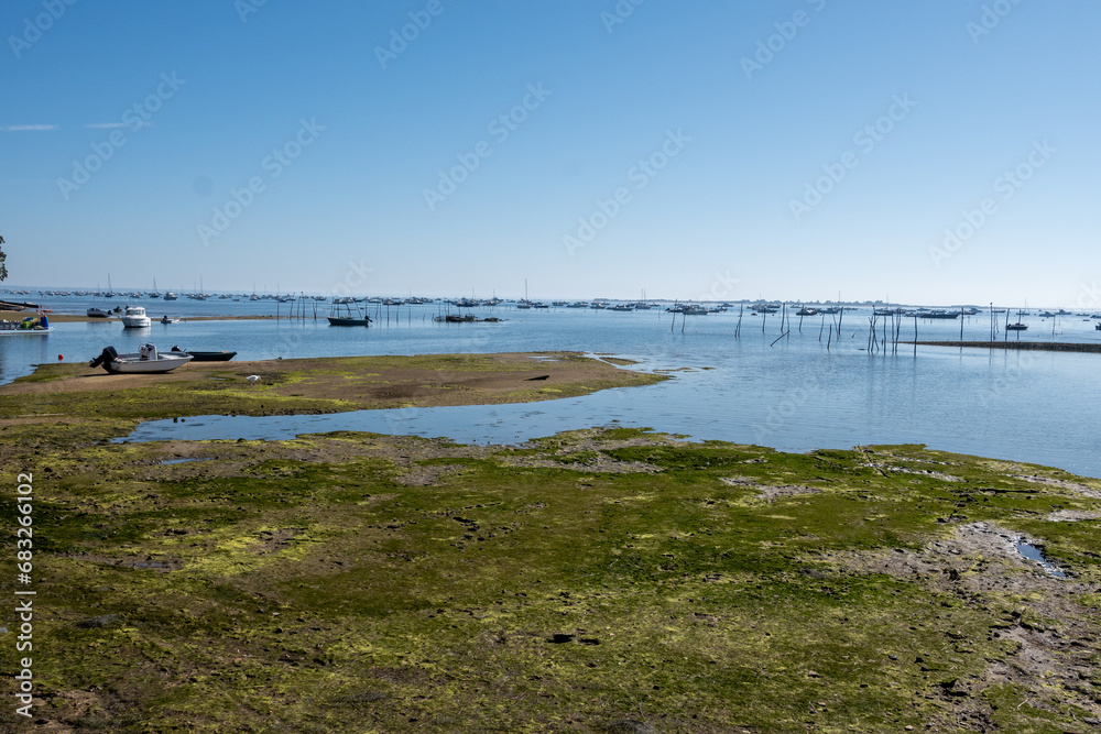View on Arcachon Bay at low tide with many fisherman's boats and oysters farms, Cap Ferret peninsula, France, southwest of Bordeaux along France's Atlantic coastline View on Arcachon Bay at low tide with many fisherman's boats and oysters farms, Cap Ferret peninsula, France, southwest of Bordeaux along France's Atlantic coastline