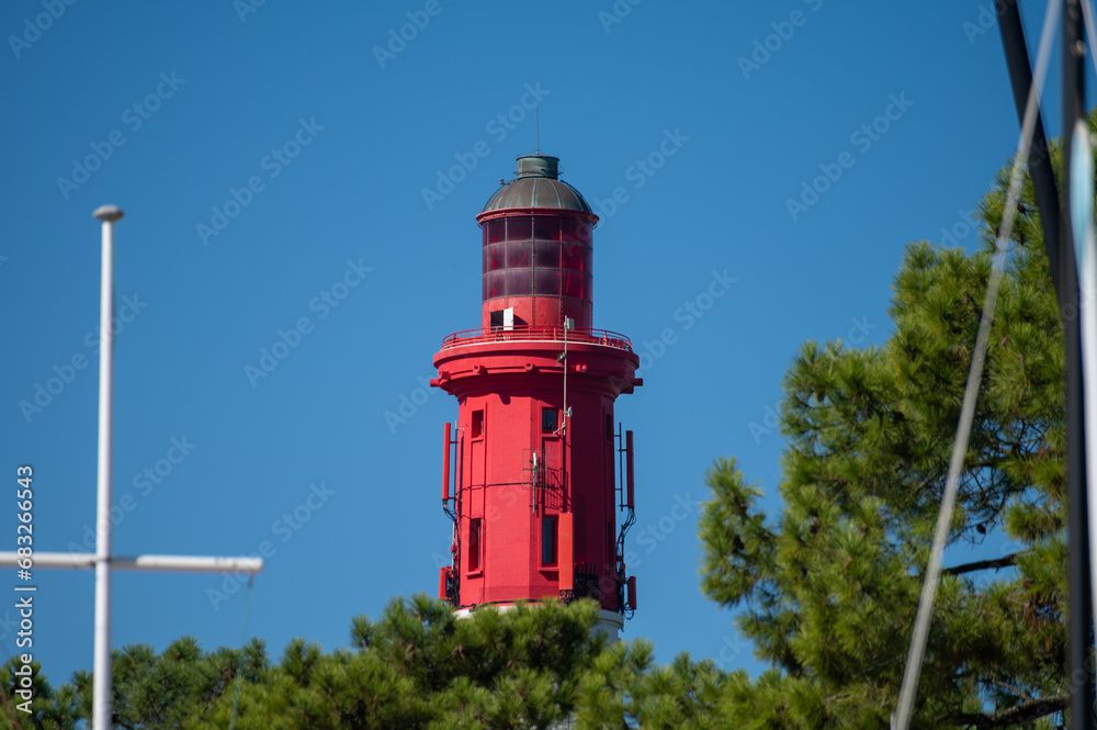 View on red lighthouse Le Phare du Cap Ferret, Arcachon Bay with many fisherman's boats and oysters farms near , Cap Ferret peninsula, France, southwest of Bordeaux, France's Atlantic coastline - obrazy, fototapety, plakaty 