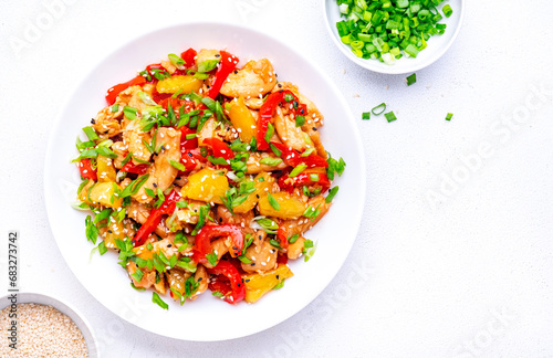 Stir fry chicken with pineapple, red paprika, chives, soy sauce and sesame seeds. Asian cuisine dish. White table background, top view