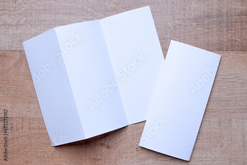 Blank trifold brochure A4 booklet on wooden background with clipping path. Folded and unfolded. photo