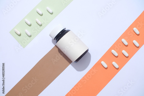 Tableau sur toile A medicine bottle without label is displayed on a background with colored strips and white pills