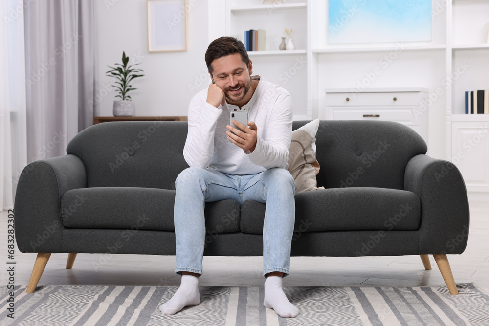Happy man having video chat via smartphone at home Happy man having video chat via smartphone at home