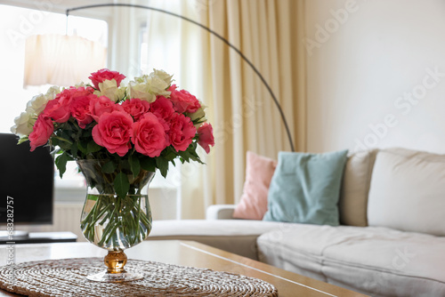 Vase with beautiful bouquet of roses on wooden table at home  space for text