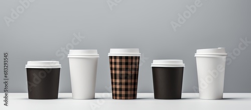 Various sizes of white takeaway coffee cups made of paper carton or cardboard are shown in an isolated collection with a checkered background an assortment of packaging mockup templates photo