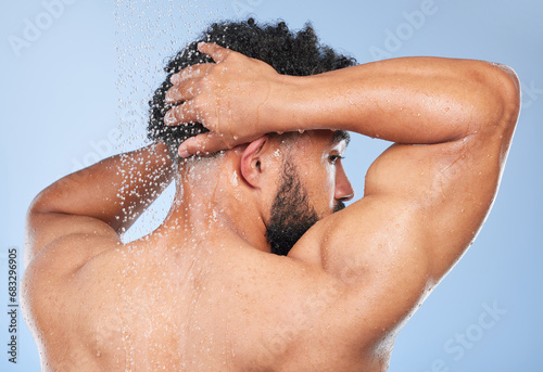 Man  shower back and splash in studio with water  wash or hygiene with self care by blue background. Person  guy and muscle with hair  wellness or health for skin  natural dermatology and body