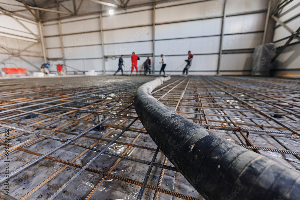 Building site, workers with pipe move concrete to reinforced structures