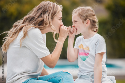 Family, secret or pinky promise with a mother and daughter outdoor in their garden or backyard together. Smile, love or happy with a young woman and her girl child at home to whisper for gossip photo