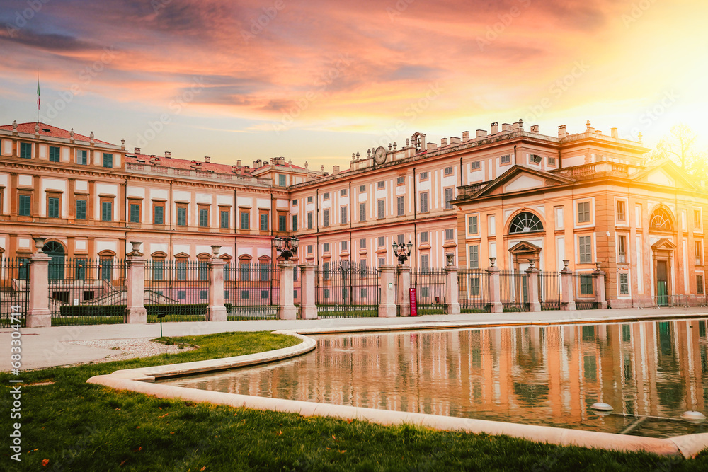 View of a portion of the Villa Reale of Monza reflected in the fountain in front at sunset with the glow of the sun