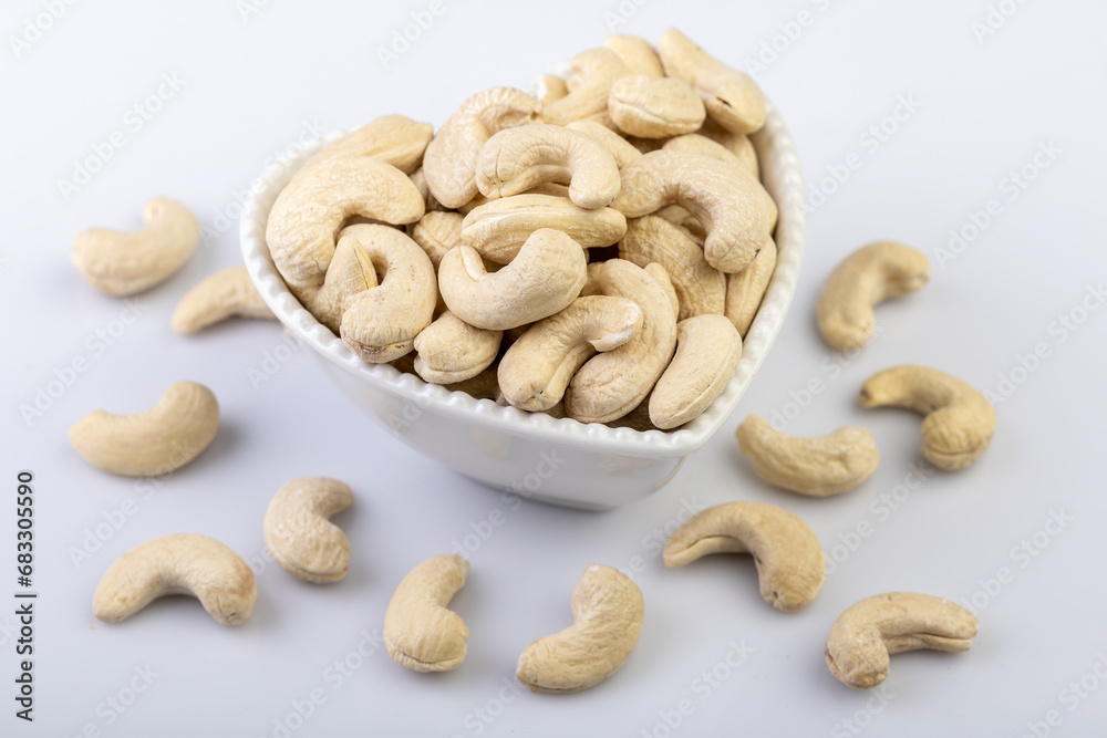 A top view of whole cashew nuts arranged beautifully in a heart-shaped bowl against a clean white background A top view of whole cashew nuts arranged beautifully in a heart-shaped bowl against a clean white background