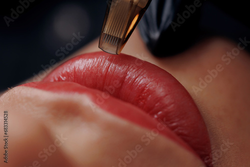 Macro photo process of applying permanent makeup tattoo of red on lips woman.