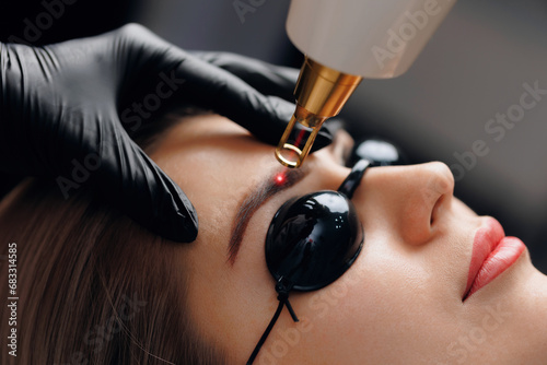 Laser removal of tattoo permanent makeup eyebrow of young woman in salon photo