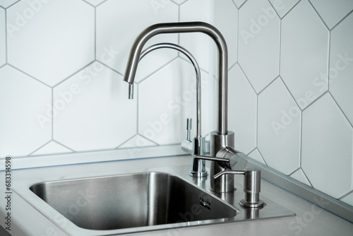 View of a metal sink with built-in faucets for running and filtered water and a liquid soap dispenser