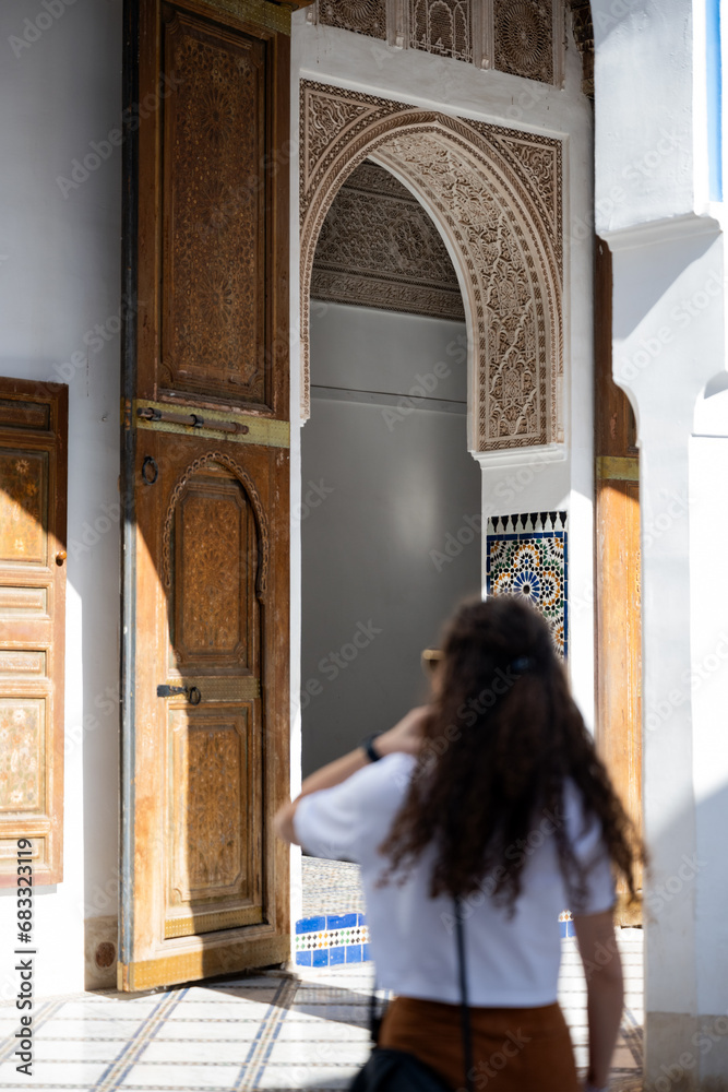 Defocused girl in the foreground visiting the Bahia Palace during a sunny day. The Bahia Palace in Marrakech is an impressive example of Moroccan architecture and design.