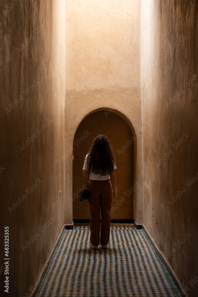Stunning view of a girl visiting the Bahia Palace during a sunny day. The Bahia Palace in Marrakech is an impressive example of Moroccan architecture and design.