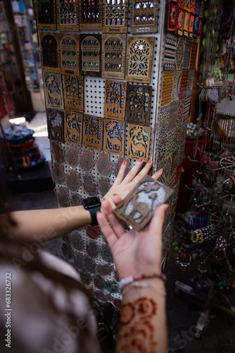 Obraz na płótnie (Selective focus) Defocused girl in the foreground choosing a magnet in Marrakesh's souk, Morocco. The souks of Marrakech are the largest in Morocco and famous globally. w salonie