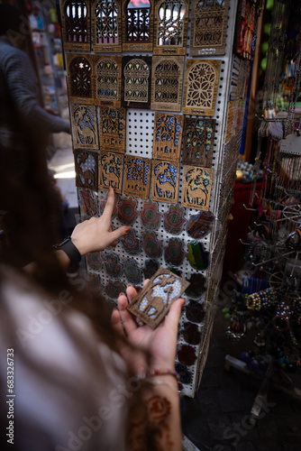 Obraz na płótnie (Selective focus) Defocused girl in the foreground choosing a magnet in Marrakesh's souk, Morocco. The souks of Marrakech are the largest in Morocco and famous globally. w salonie