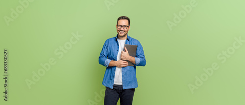 Portrait of handsome entrepreneur holding digital tablet and smiling at camera on green background photo