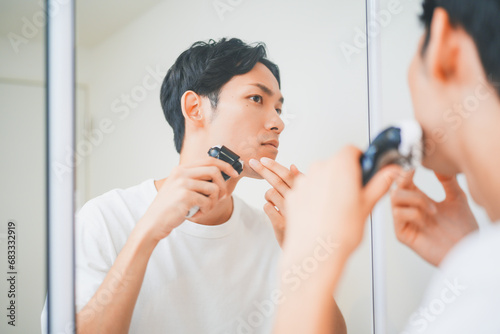 洗面所で髭を剃る男性