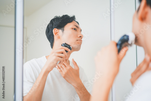 洗面所で髭を剃る男性