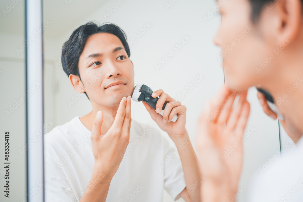 洗面所で髭を剃る男性 洗面所で髭を剃る男性