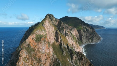 Top view of rocky mountains islands in ocean. Clip. Fabulous landscape of rocky island in ocean on sunny day. Cinematic landscape of rocky cape of island in sea