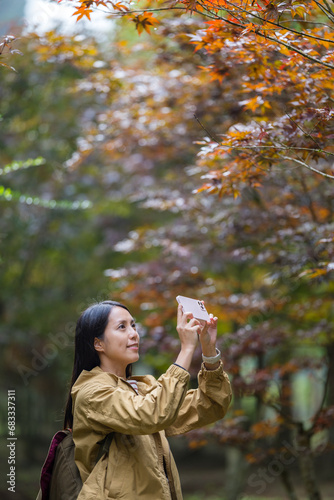Hike woman use of mobile phone to take photo in autumn season