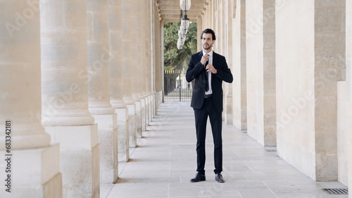 Young confident businessman in a formal suit by the columns of the buildings. Action. Elegant male portrait.