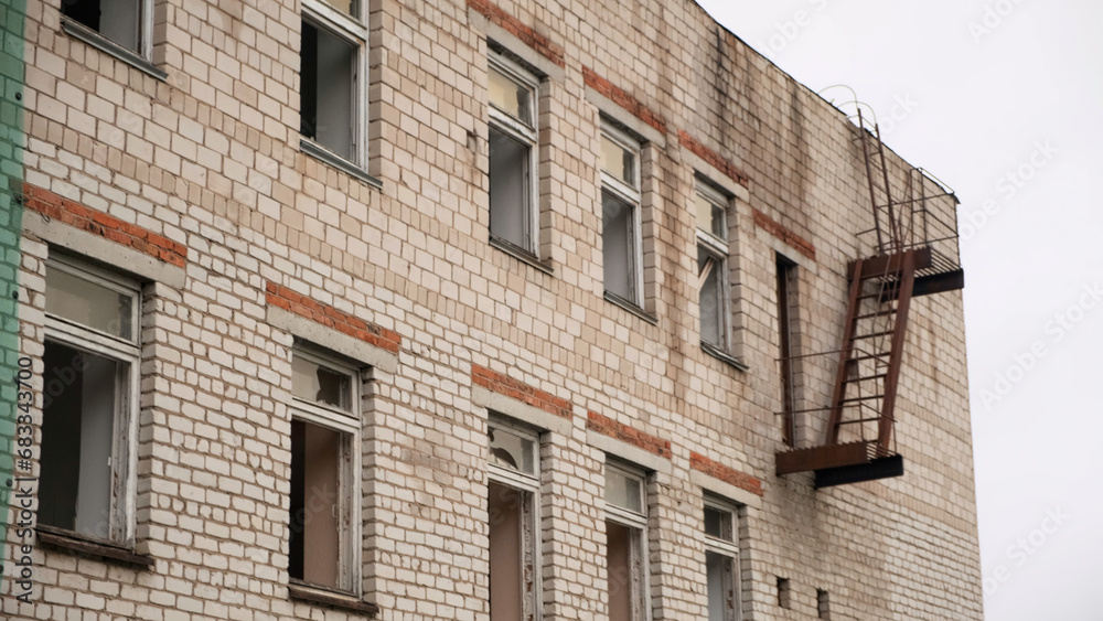 Fototapeta premium Old abandoned brick building used for housing and rental apartments or hospital. Clip. Broken windows of a ruined house.