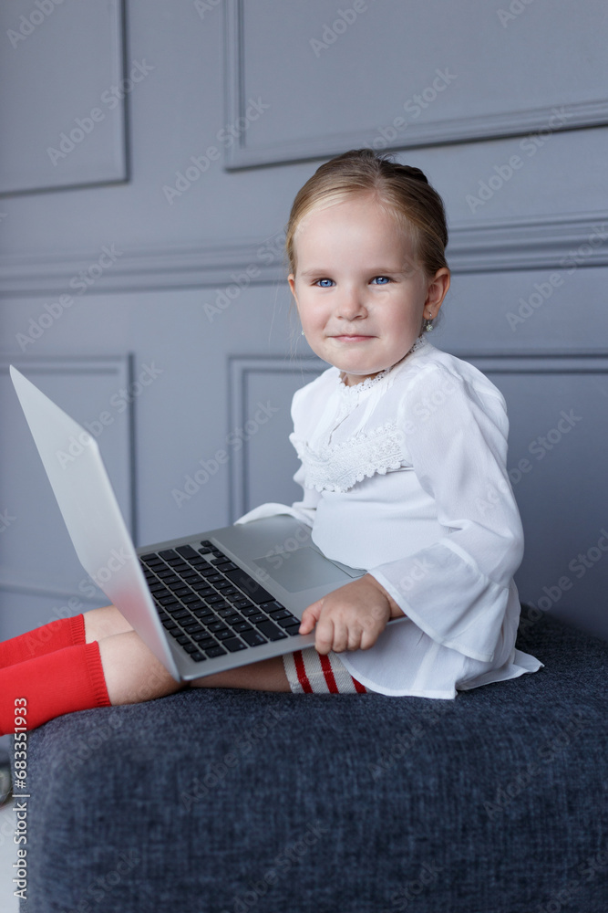 Profile image of a cute smiling little girl, working on laptop, looking at the camera. Profile image of a cute smiling little girl, working on laptop, looking at the camera.