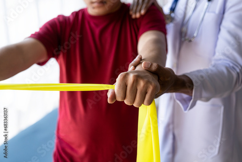 Asian male patient doing physical therapy with caregiver Attractive caregiver helping and supporting man with arm and shoulder muscle injury