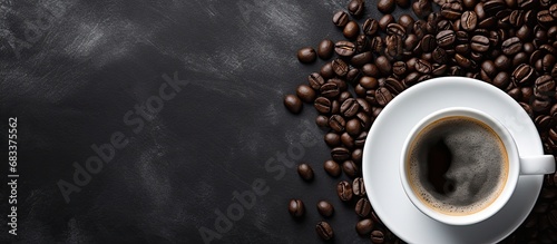 Top view of a ceramic cup filled with black coffee and milk foam accompanied by a napkin and a sack of roasted coffee beans on a dark table
